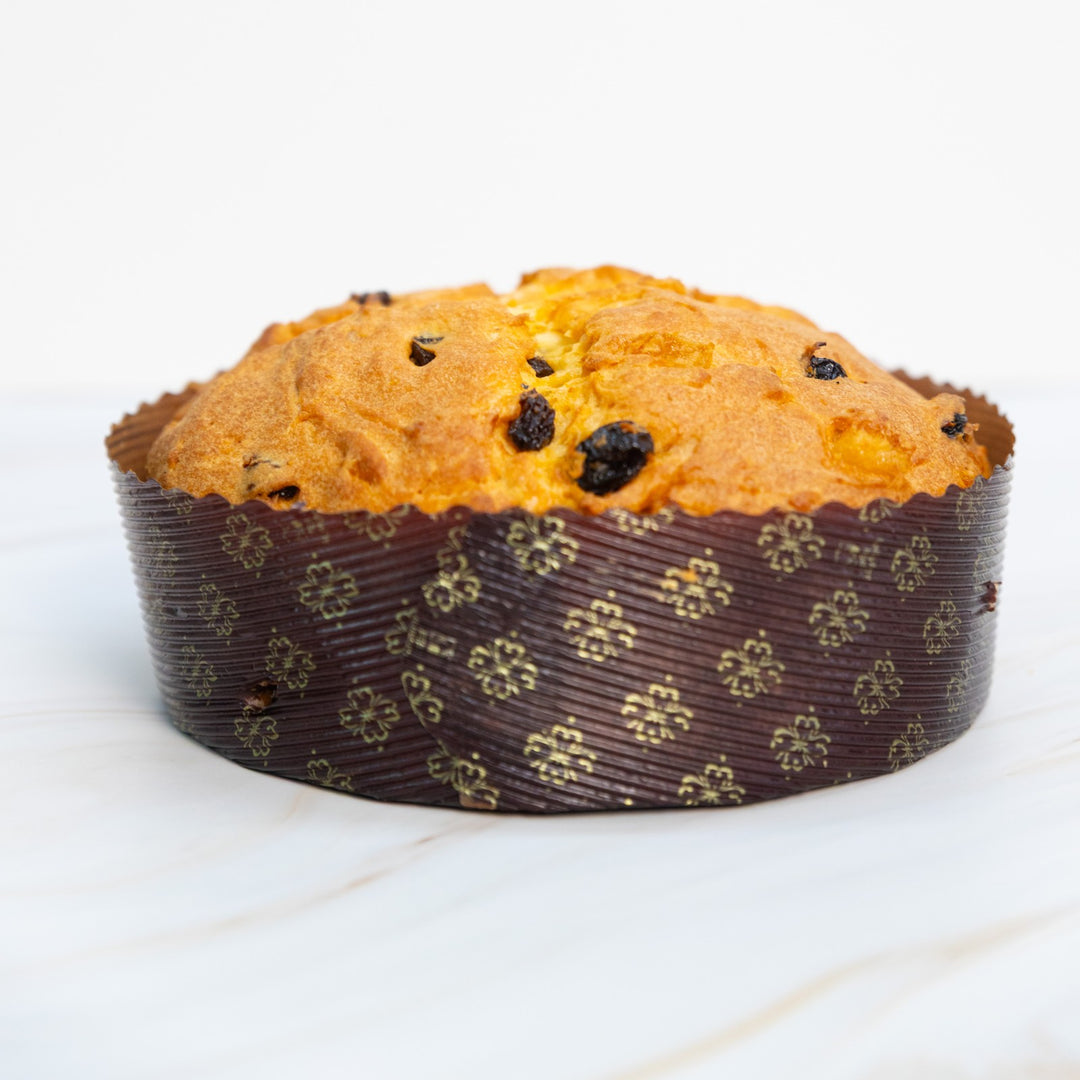 Panettone con uvetta e canditi nel pirottino decorato, vista frontale a distanza