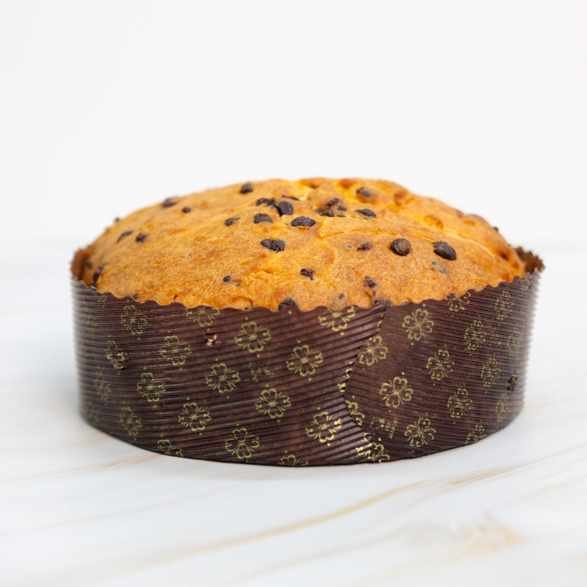 Panettone con gocce di cioccolato, vista frontale a distanza su piano in marmo